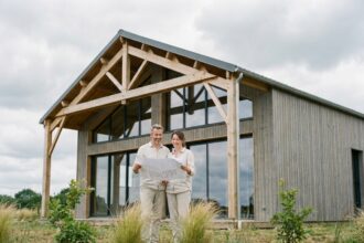 Couple devant leur maison ossature bois neuve près de Nantes avec plans d'architecte