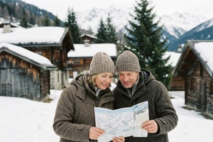 Couple d'âge moyen examinant une carte devant des chalets enneigés
