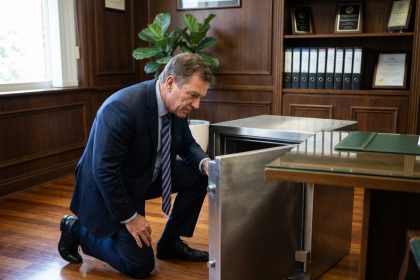 Homme d'affaires en costume examine un coffre-fort en bureau